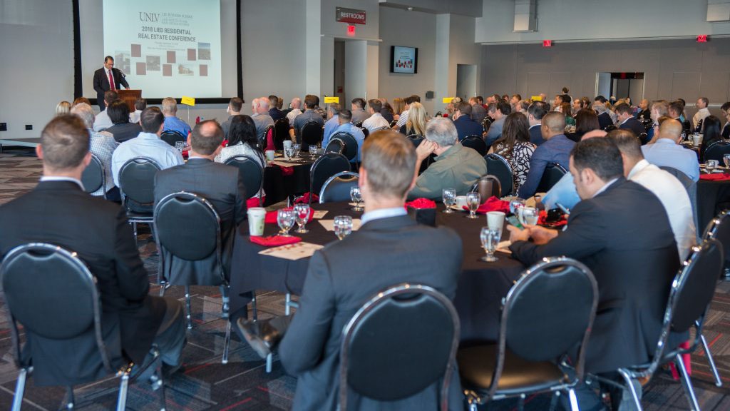 Man in suit presenting to a room of businesspeople
